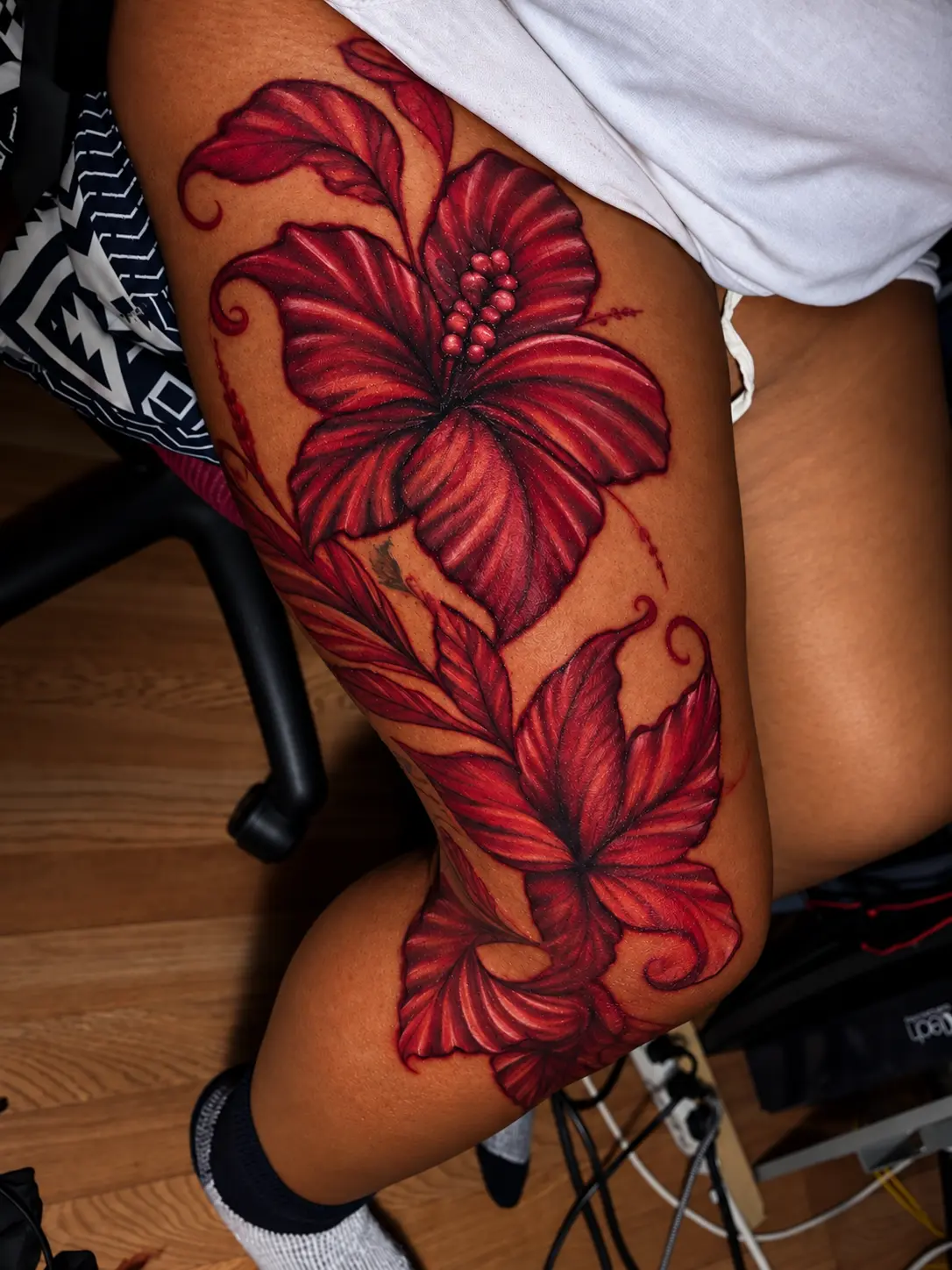 Color-corrected red botanical thigh and knee tattoo by Krayonz